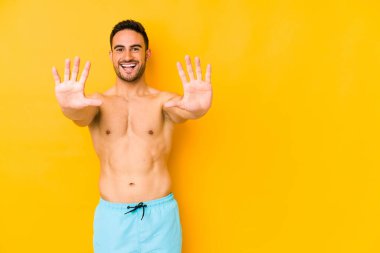 Sarı arka planda mayosu olan genç, beyaz bir adam. 10 numarayı elleriyle çizen beyaz bir adam..