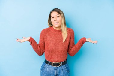 Kafkasyalı genç bir kadın yalnız poz veriyor. Kafası karışık ve omuz silkiyor. Kopya alanını tutmak için..