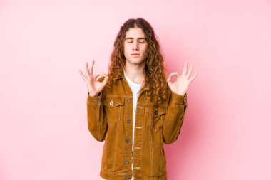 Uzun saçlı genç adam izole edilmiş poz veriyor. Sıkı çalışma gününden sonra rahatlıyor. Yoga yapıyor..