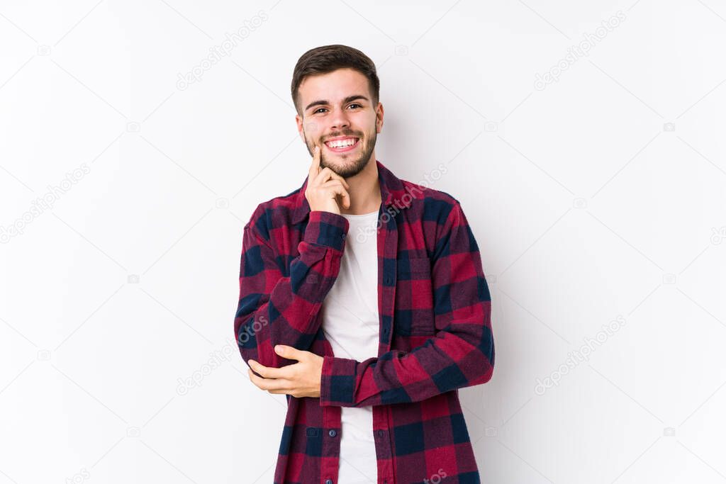 Young caucasian man posing in a white background isolated smiling happy and confident, touching chin with hand.
