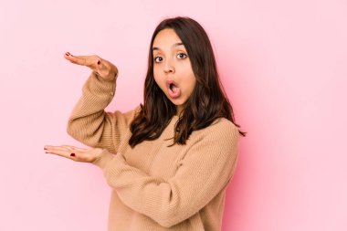 Latin kökenli genç bir kadın şok olmuş ve hayrete düşmüş. Ellerinin arasında bir kopya alanı tutuyor..