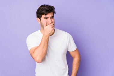 Mor arka planda izole edilmiş genç bir adam. Düşünceli bir şekilde bir fotokopi odasına bakıyor. Ağzı elle kapatıyor..