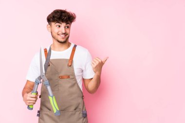 Genç Arap bahçıvan parmak uzakta noktalar izole, gülüyor ve kaygısız.