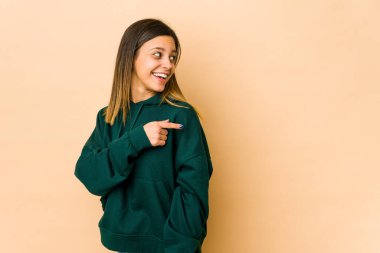 Bej arka planda soyutlanmış genç bir kadın. Gülümsüyor, neşeli ve keyifli görünüyor..