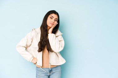 Mavi arka plandaki genç Hintli kadın sıkılmış, yorgun ve dinlenmeye ihtiyacı var..