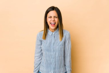 Bej arka planda izole edilmiş genç bir kadın çok kızgın, öfkeli, hayal kırıklığına uğramış.