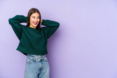 Mor arka planda soyutlanmış beyaz bir kadın. Kendinden emin, elleri başının arkasında..