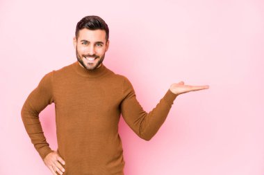 Pembe arka planda genç beyaz bir adam avuçta bir fotokopi alanı ve belinde bir el daha gösteriyor..