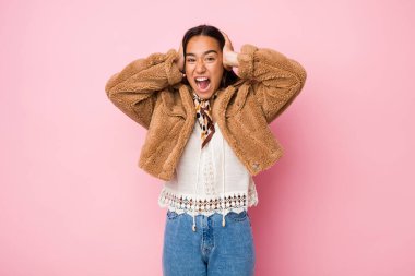 Genç melez Hintli kadın kısa bir koyun postu giyiyor kulaklarını kulaklarıyla örtüyor yüksek sesli sesler duymamaya çalışıyor..