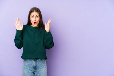 Mor arka planda izole genç beyaz kadın şaşırdı ve şok oldu..