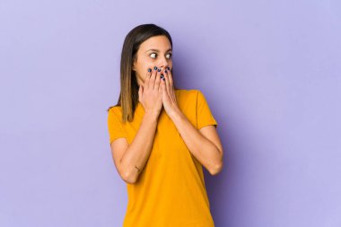 Mor arka planda izole edilmiş genç bir kadın. Bir fotokopi odasına dikkatlice bakıyor. Ağzını eliyle kapatıyor..