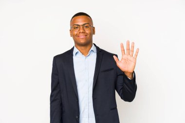 Genç iş adamı beyaz arka planda izole edilmiş beş numarayı parmaklarıyla gülümsüyor..