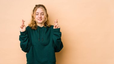 Beyazlı genç bir kadın bej arka planda izole edilmiş şans dilemek için şans diliyor.