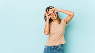 Mavi arka planda izole edilmiş genç bir kadın, gözlerde sorun olmadığını gösteriyor.