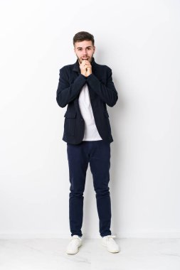 Tüm vücudu beyaz tenli genç adam şans için dua ediyor, hayret içinde ve ağzı açık bir şekilde önüne bakıyor..