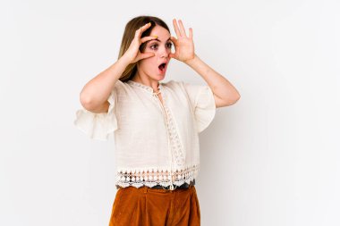 Beyaz arka planda izole genç beyaz kadın bir başarı fırsatı bulmak için gözlerini açık tutuyor..