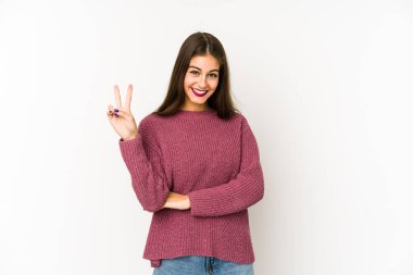 Beyaz arka planda izole edilmiş genç beyaz kadın iki numarayı parmaklarıyla gösteriyor..