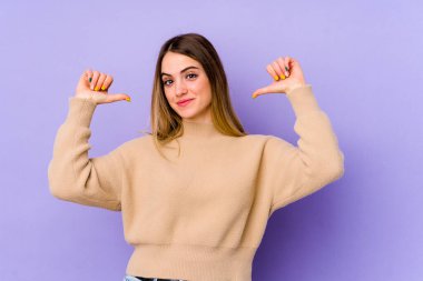 Mor arka planda izole genç beyaz kadın gururlu ve kendinden emin hissediyor, örnek olarak..