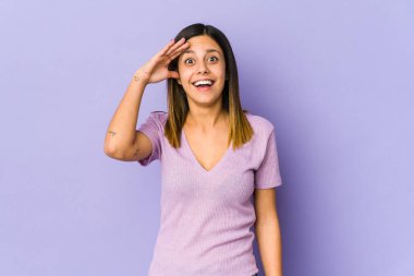 Mor arka planda izole edilmiş genç bir kadın yüksek sesle bağırıyor, gözleri açık ve elleri gergin tutuyor..