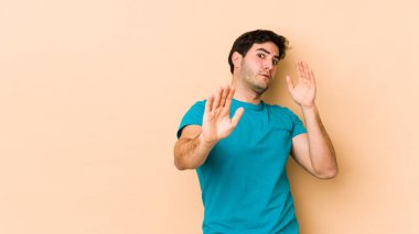 Bej arka planda izole genç bir adam yakın bir tehlike nedeniyle şoka uğruyor.