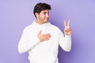 Mor arka planda izole edilmiş genç adam yemin ediyor, elini göğsüne koyuyor..
