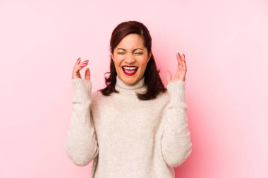 Orta yaşlı Latin bir kadın pembe bir arka planda izole edilmiş neşeli bir şekilde gülüyor. Mutluluk kavramı.