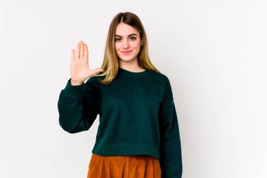 Beyaz arka planda izole edilmiş genç beyaz kadın gülümseyerek beş numarayı parmaklarıyla gösteriyor..