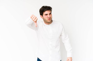 Beyaz arka planda izole edilmiş genç bir adam baş parmağını aşağı gösteriyor ve hoşlanmadığını ifade ediyor..