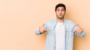 Bej arka planda izole edilmiş genç adam parmakları aşağıda, olumlu hisler içinde..