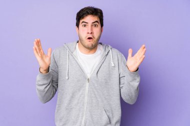 Mor arka planda kalan genç adam zaferi ya da başarıyı kutluyor, şaşırıyor ve şok oluyor..