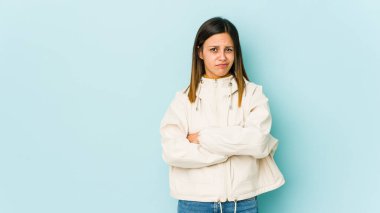 Mavi arka planda izole edilmiş genç bir kadın. Kameraya alaycı bir ifadeyle bakıyor..