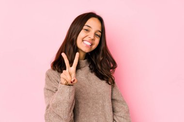 Genç, Latin kökenli, neşeli ve tasasız bir kadın parmaklarıyla barış sembolü gösteriyor..