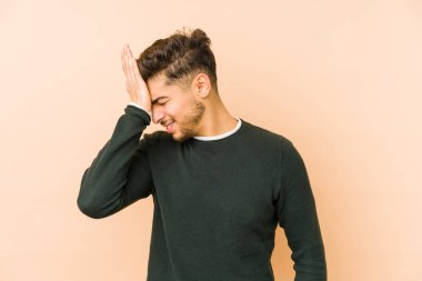 Bej bir arka planda izole edilmiş genç bir Arap bir şeyi unutuyor. Alnına avuç içi ve kapalı gözlerle vuruyor..