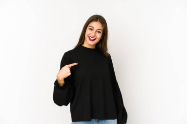 Beyaz arka planda yaşayan beyaz tenli genç bir kadın gömlek fotokopi alanını elle işaret ediyor, gururlu ve kendinden emin