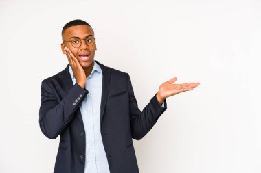 Beyaz arka planda izole edilmiş genç Latin bir adam avuç içinde fotokopi alanı tutuyor, el üstünde tutuyor. Şaşırmış ve mutlu..