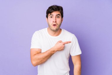 Mor arka planda izole genç adam yan tarafı işaret ediyor.
