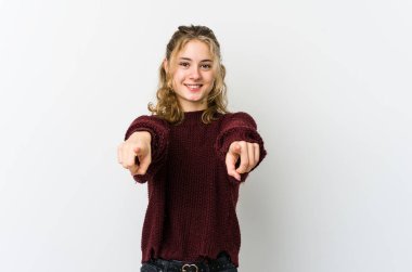 Beyaz arka planda beyaz saçlı genç beyaz kadın öne doğru gülümsüyor..