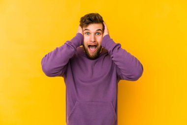 Sarı arka planda izole edilmiş genç beyaz bir adam çığlık atıyor, çok heyecanlı, tutkulu, bir şeyden memnun..