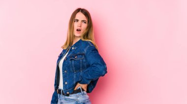 Pembe arka planda izole edilmiş beyaz bir kadın sırt ağrısı çekiyor..