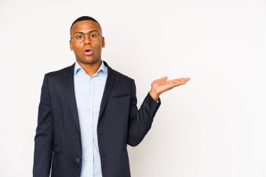 Beyaz arka planda izole edilmiş genç iş adamı, avuç içinde kopya alanı bulundurmaktan etkilenmiş..