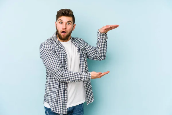 Young Caucasian Man Isolated Blue Background Shocked Amazed Holding Copy — Stock Photo, Image