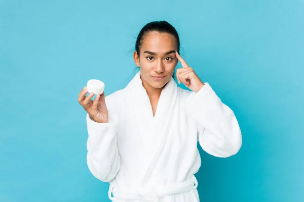 Joven Indio Raza Mixta Sosteniendo Una Crema Hidratante Apuntando Sien —  Fotos de Stock