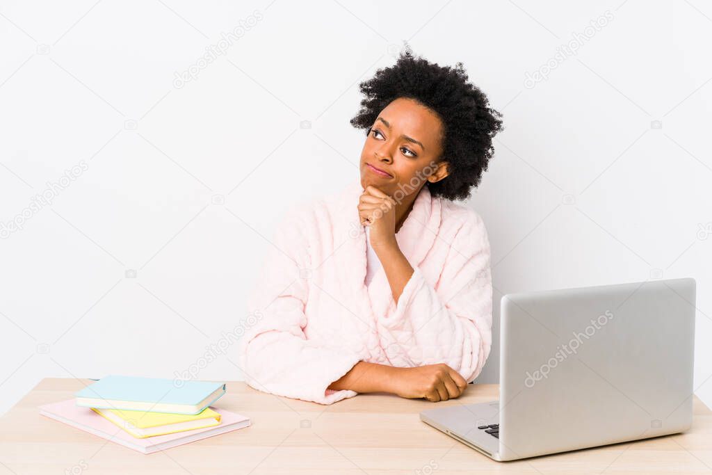 Middle aged african american woman working at home isolated looking sideways with doubtful and skeptical expression.