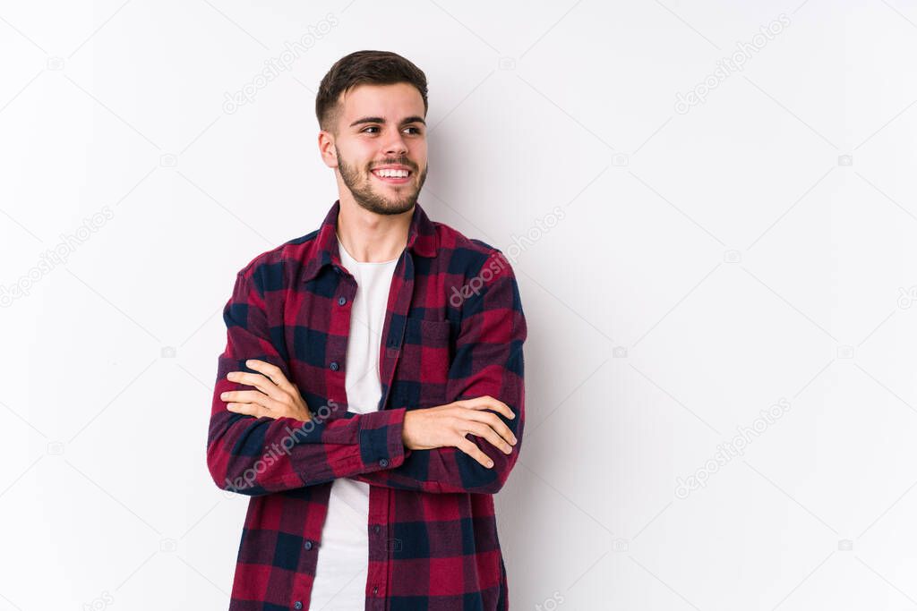 Young caucasian man posing in a white background isolated smiling confident with crossed arms.