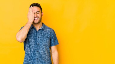 Kafkasyalı genç adam sarı fırında izole edilmiş. Yüzünün yarısını palmiye ile kaplayarak eğleniyor..