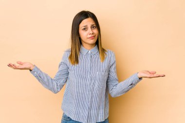 Bej arka planda izole edilmiş genç bir kadın sorgulama sırasında omuz silkiyor ve şüphe ediyor..