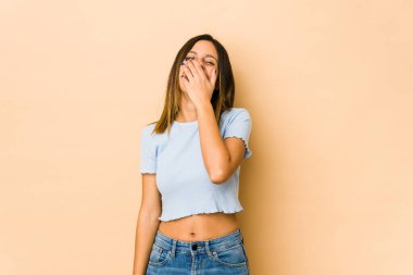 Bej arka planda izole edilmiş genç bir kadın gülüyor, kaygısız, doğal bir duygu..