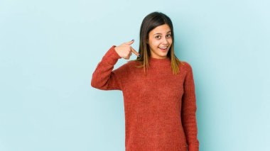 Mavi arka planda yaşayan genç bir kadın gömlek fotokopisini elle gösteriyor, gururlu ve kendinden emin.