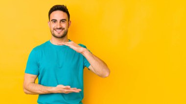 Kafkasyalı genç adam sarı fırında iki eliyle bir şey tutuyor, ürün sunumu..