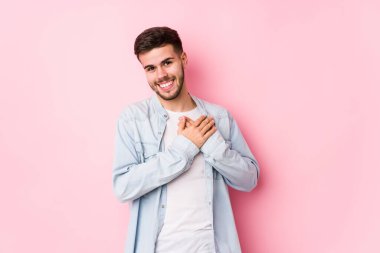 Beyaz arka planda yalnız poz veren beyaz tenli genç bir iş adamı, avuçlarını göğsüne bastıran dostane bir ifadeye sahiptir. Aşk konsepti.